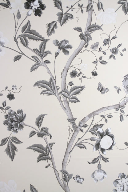SUMMER PALACE CHARCOAL wallpaper by Laura Ashley at Arte Fresca Outlet. This exquisite paper wallcovering features a detailed floral and botanical pattern with graceful plant tendrils, large blossoms, leaves, butterflies, and a delicate bird, all rendered in an elegant black-white-grey scale on a warm, cream-colored background, embodying classic elegance and romantic Asian poetry.