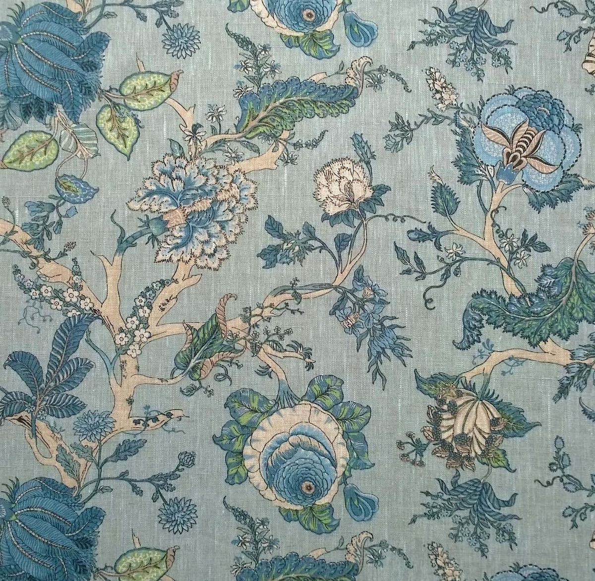 Villars Lin Duck Egg fabric coupon by Arte Fresca Outlet, showing a large view of the detailed botanical pattern on a soft duck egg blue background with a linen-like texture. This printed 100% cotton fabric piece features imaginative flowers in various blue tones, with fresh green and creamy beige accents for branches and blossoms, highlighting its smooth feel and elegant design.