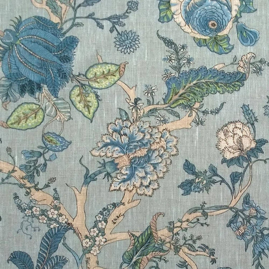 Close-up of Villars Lin Duck Egg fabric coupon from Arte Fresca Outlet, revealing the fine details of the botanical print. Various blue flowers with green and creamy beige foliage are set against a soft duck egg blue background on this smooth, printed cotton fabric piece, showcasing its subtle texture and rich colors.
