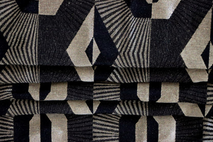 Voisin Black fabric by Arte Fresca Outlet arranged in folds, envisioning its application as a stylish Roman blind that adds a graphic touch to any window.