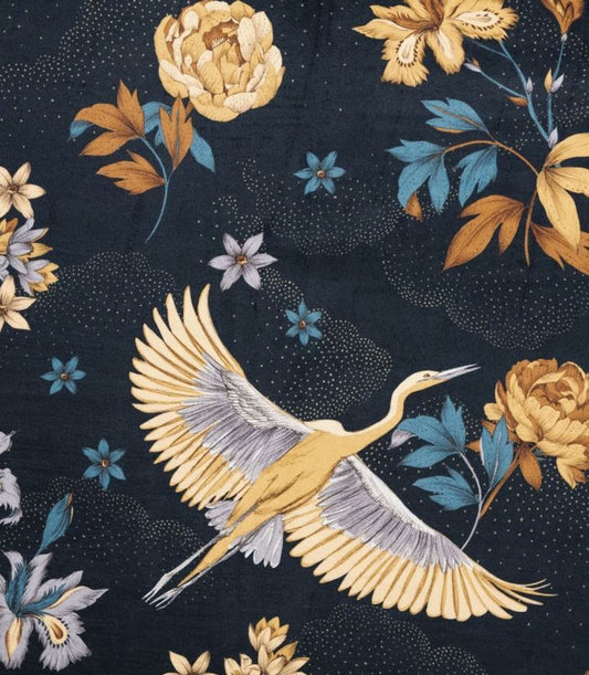 YUME VELOURS MIDNIGHT BLUE fabric by Arte Fresca Outlet draped loosely on a light upholstered chair, illustrating the scale of its dramatic botanical pattern with an elegant flying crane. The golden-yellow/ochre blossoms and muted blue/green foliage on deep midnight blue velour give a sense of its grand design proportions and suitability for upholstery (50,000 Martindale).